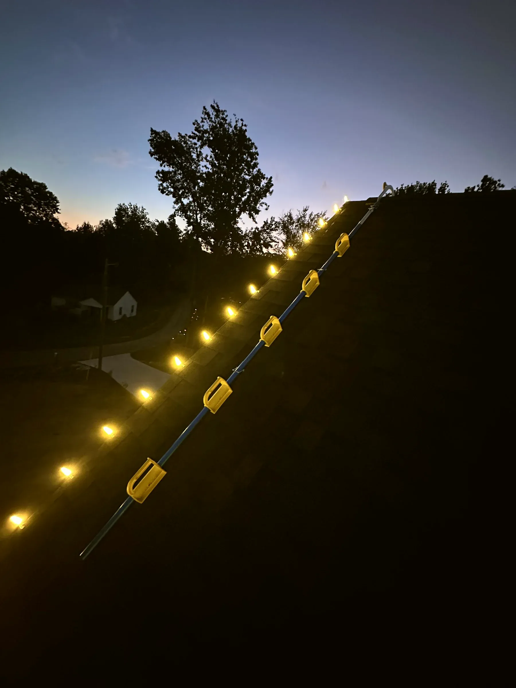 Bulbs clipped along a roof ridge at dusk, each one held by its own clip.